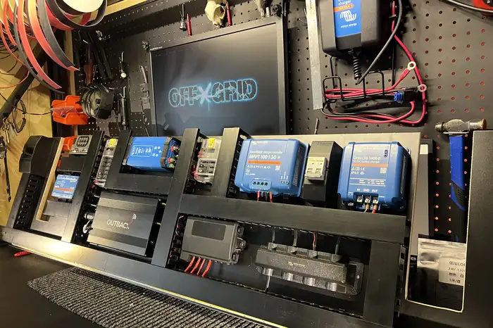Custom powerboard on the bench with Victron chargers, an inverter, fuse blocks and a busbar